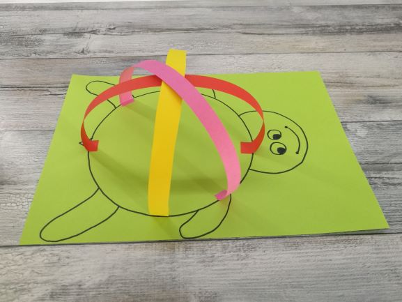 kolorowe paski papieru przyklejone do rysunku żółwia tworzą skorupę 