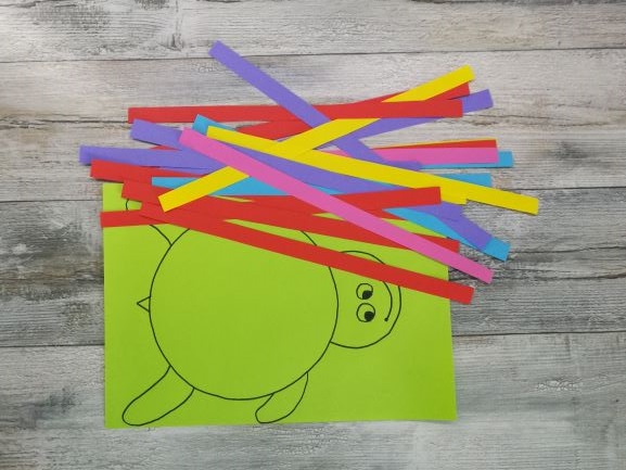 kartka z narysowanym żółwiem i kolorowe paski papieru